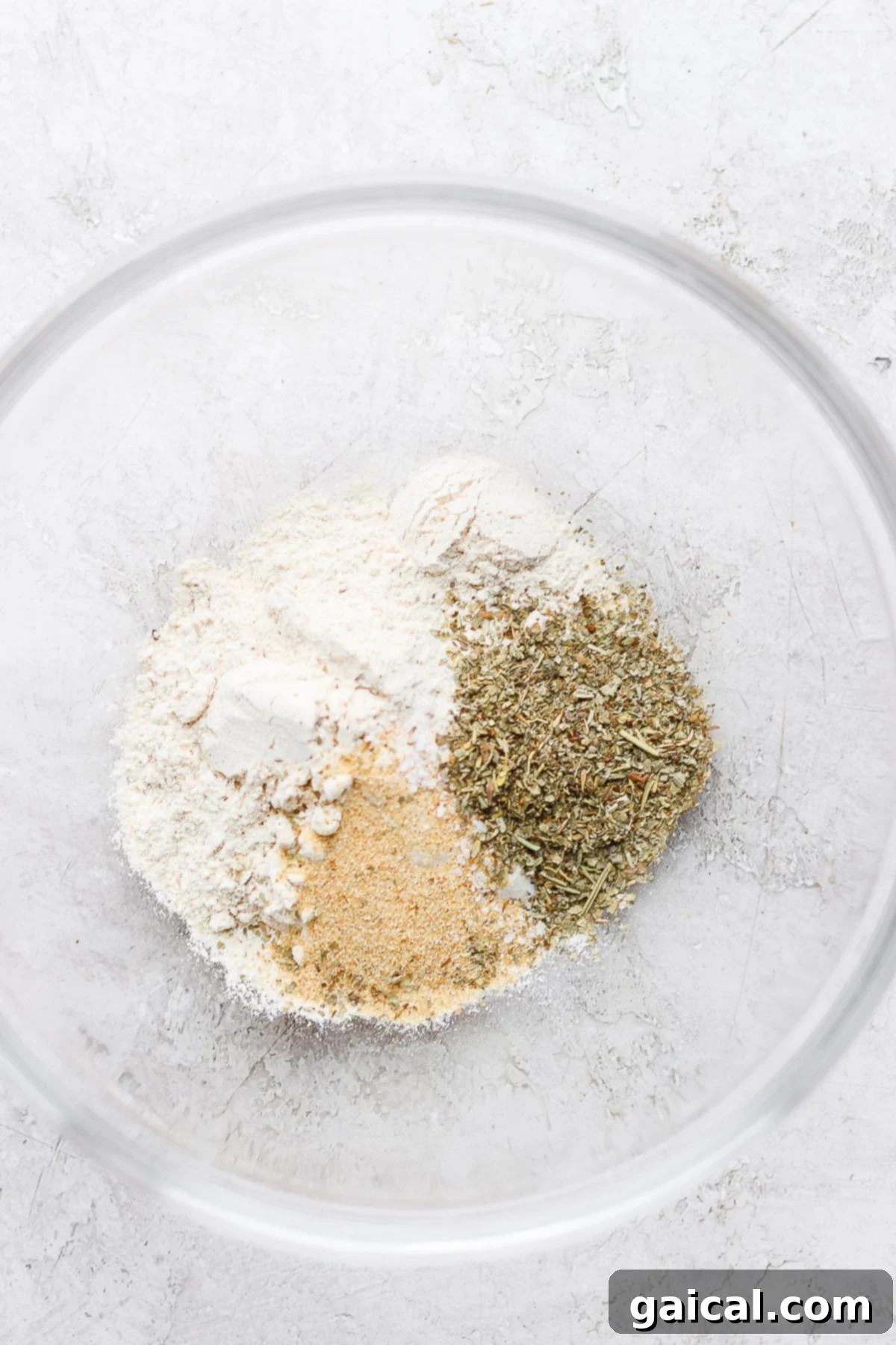 Flour and spices in a clear bowl, ready for dredging chicken for piccata.
