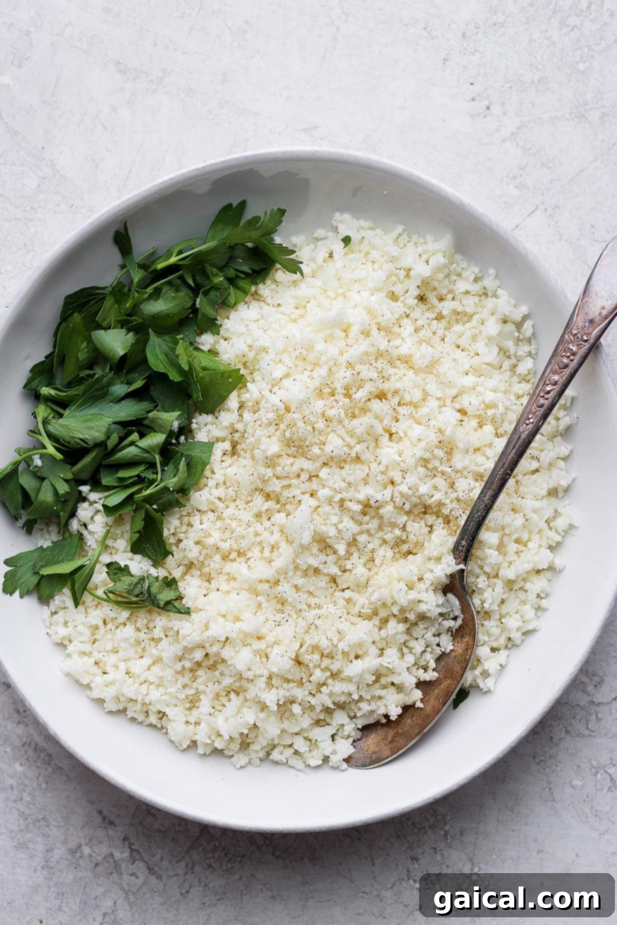 Cauliflower Grains 2 Cauliflower rice in a bowl, garnished with fresh herbs, ready to be served.