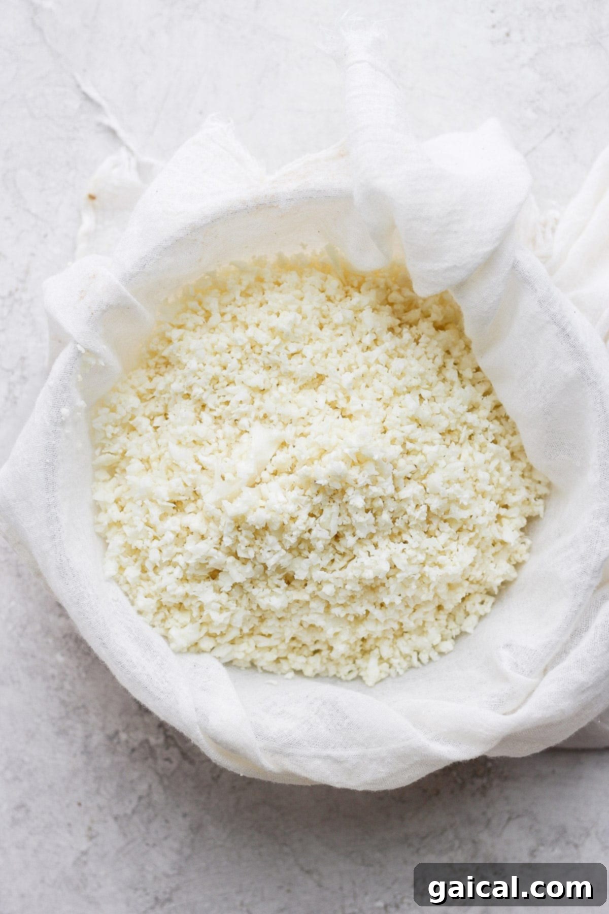 Cauliflower Grains 4 Cauliflower rice in a tea towel being squeezed to remove moisture.
