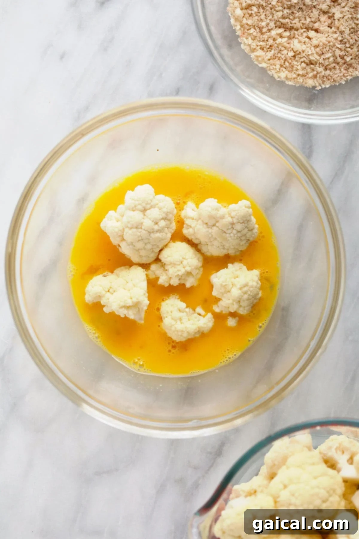 Cauliflower florets coated in egg wash, ready for the almond flour mixture.
