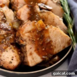 Sliced pork tenderloin served on a plate with gravy.