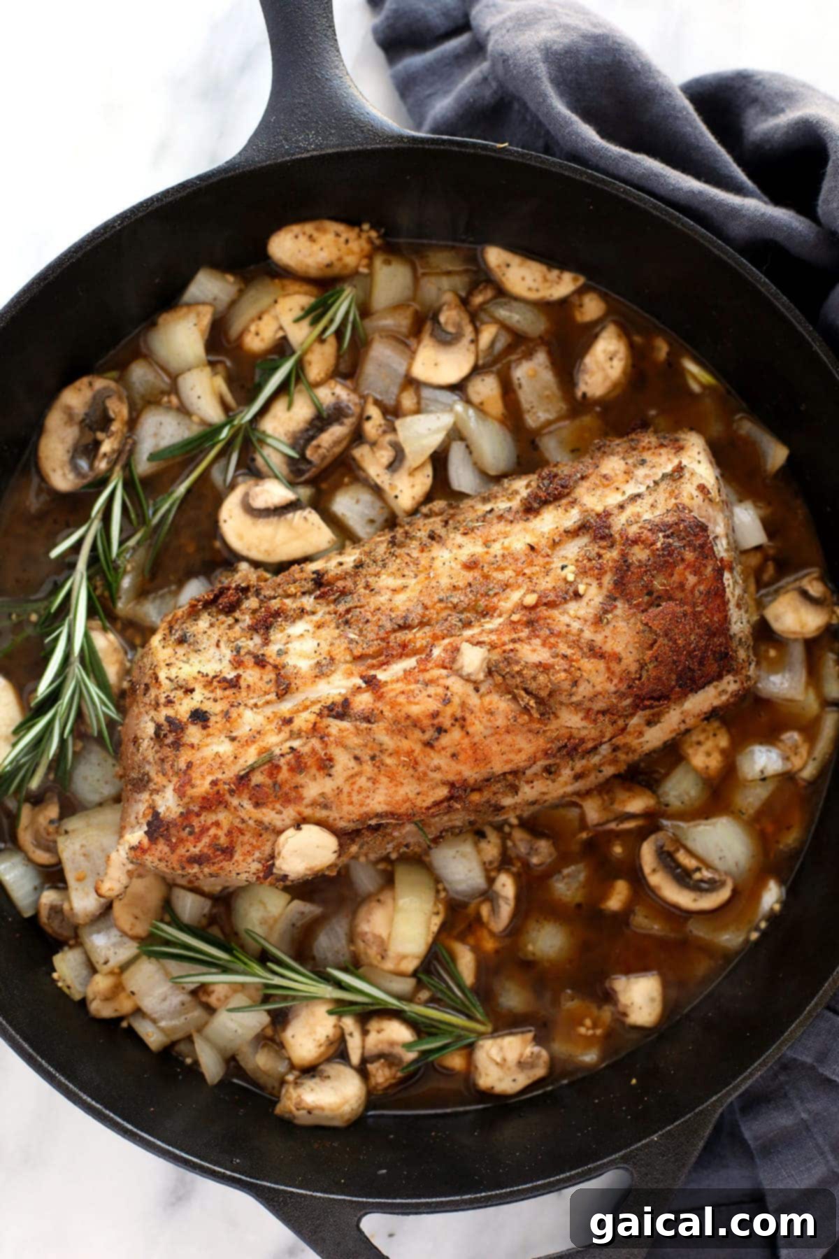 Sliced pork tenderloin served in a cast iron pan with abundant mushroom gravy.