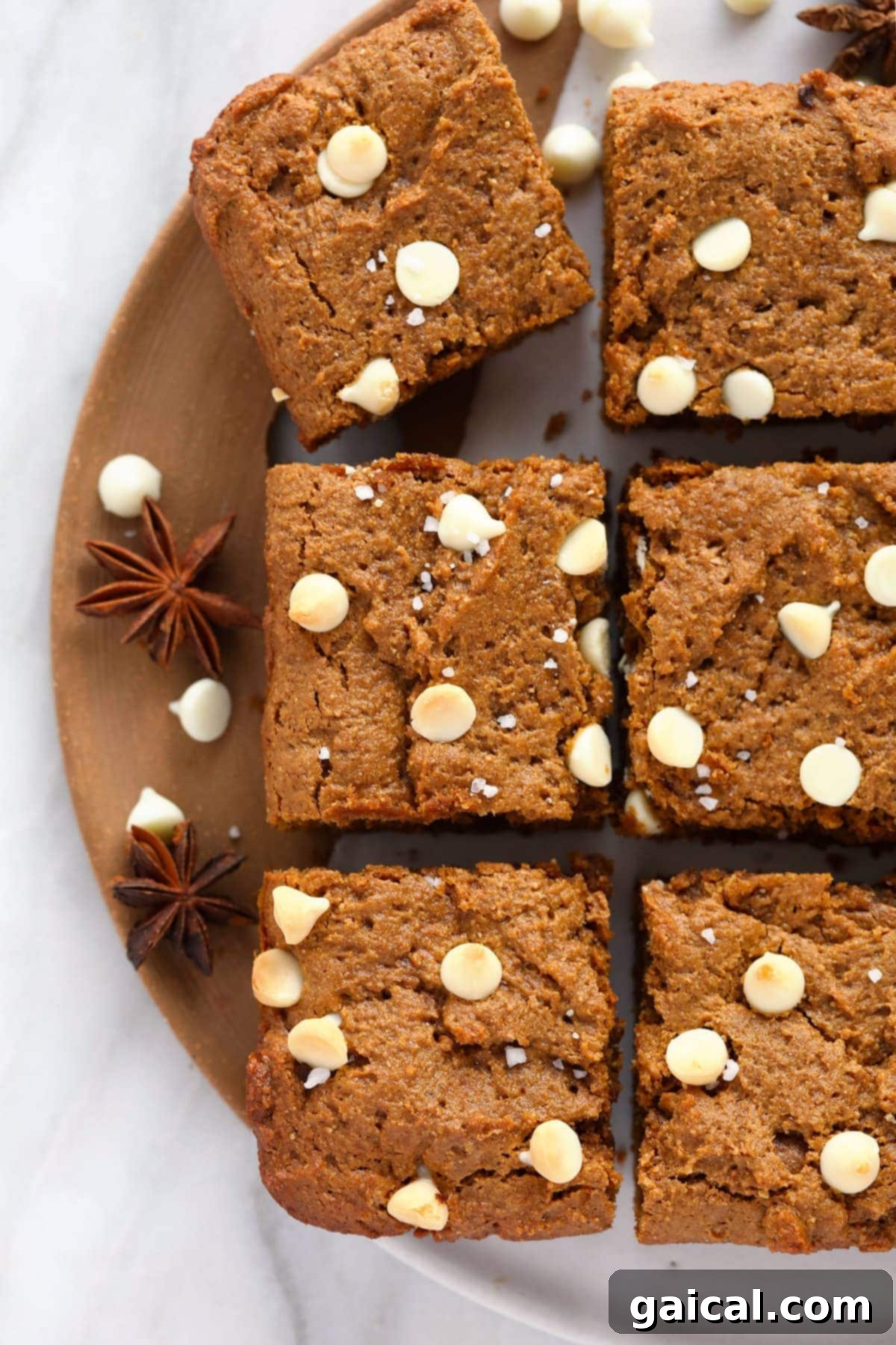 Spiced Gingerbread Bars 6 A close-up of gingerbread cookie bars topped with white chocolate chips and a sprinkle of sea salt, invitingly presented.
