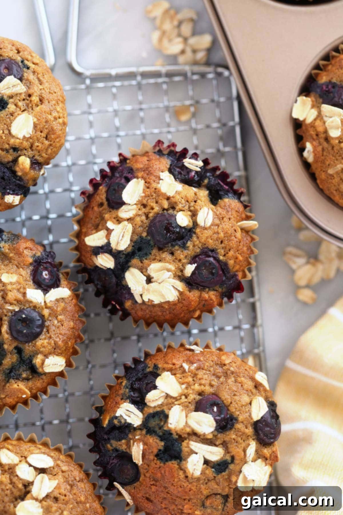 Golden-brown blueberry oatmeal muffins, topped with a sprinkle of rolled oats, cooling on a wire rack.