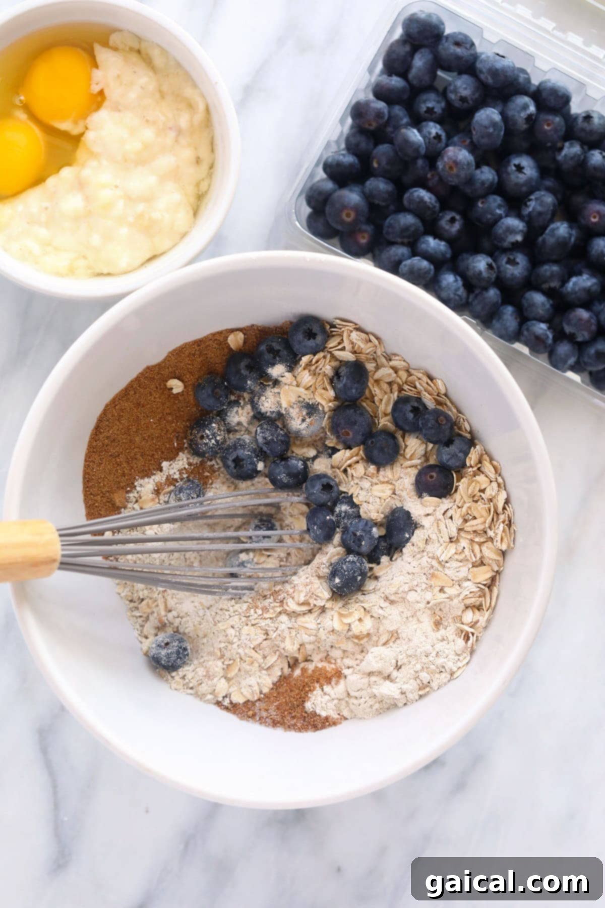 Individual ingredients for blueberry oatmeal muffins laid out in separate bowls, ready for mixing.
