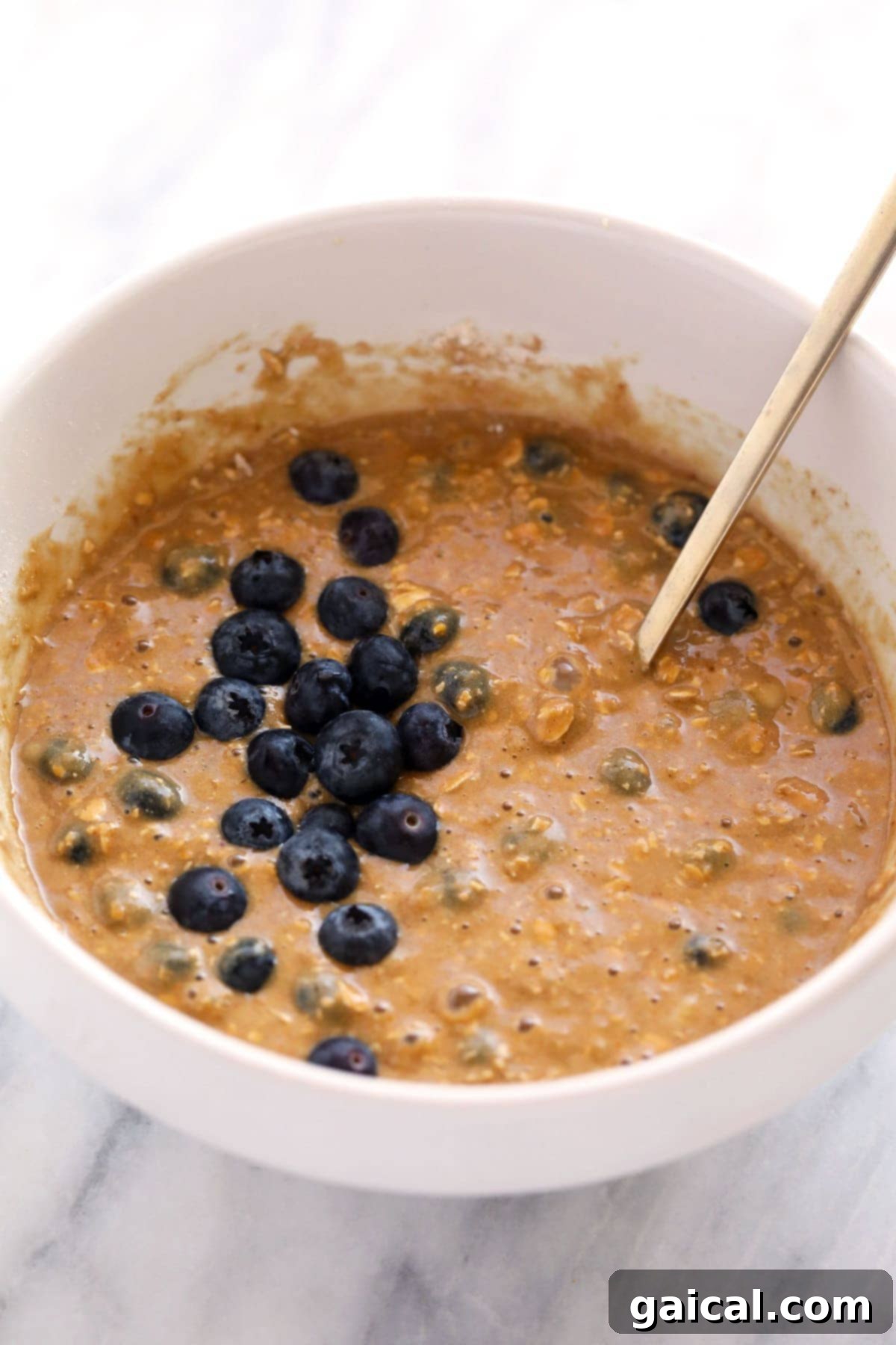 Smooth and thick blueberry oatmeal muffin batter in a mixing bowl, ready for baking.