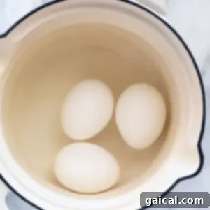 Tre egg i en gryte på en benkeplate i marmor.