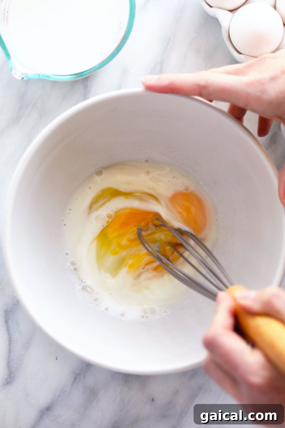 Whisking Eggs and Milk for Scrambled Eggs A bowl containing raw eggs and milk, perfectly whisked and blended, prepared for cooking into fluffy scrambled eggs.