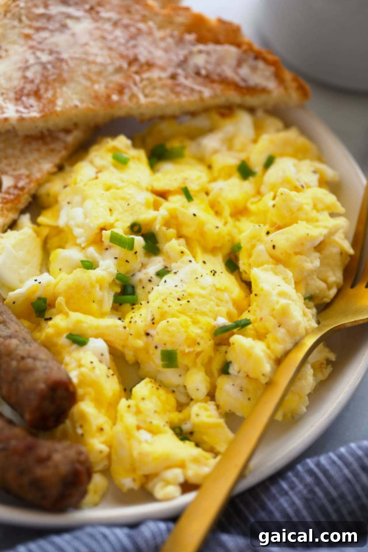 Scrambled Eggs with Classic Breakfast Sides A complete and inviting breakfast plate featuring flawlessly cooked scrambled eggs, alongside golden toast and savory sausage links, perfectly arranged for serving.