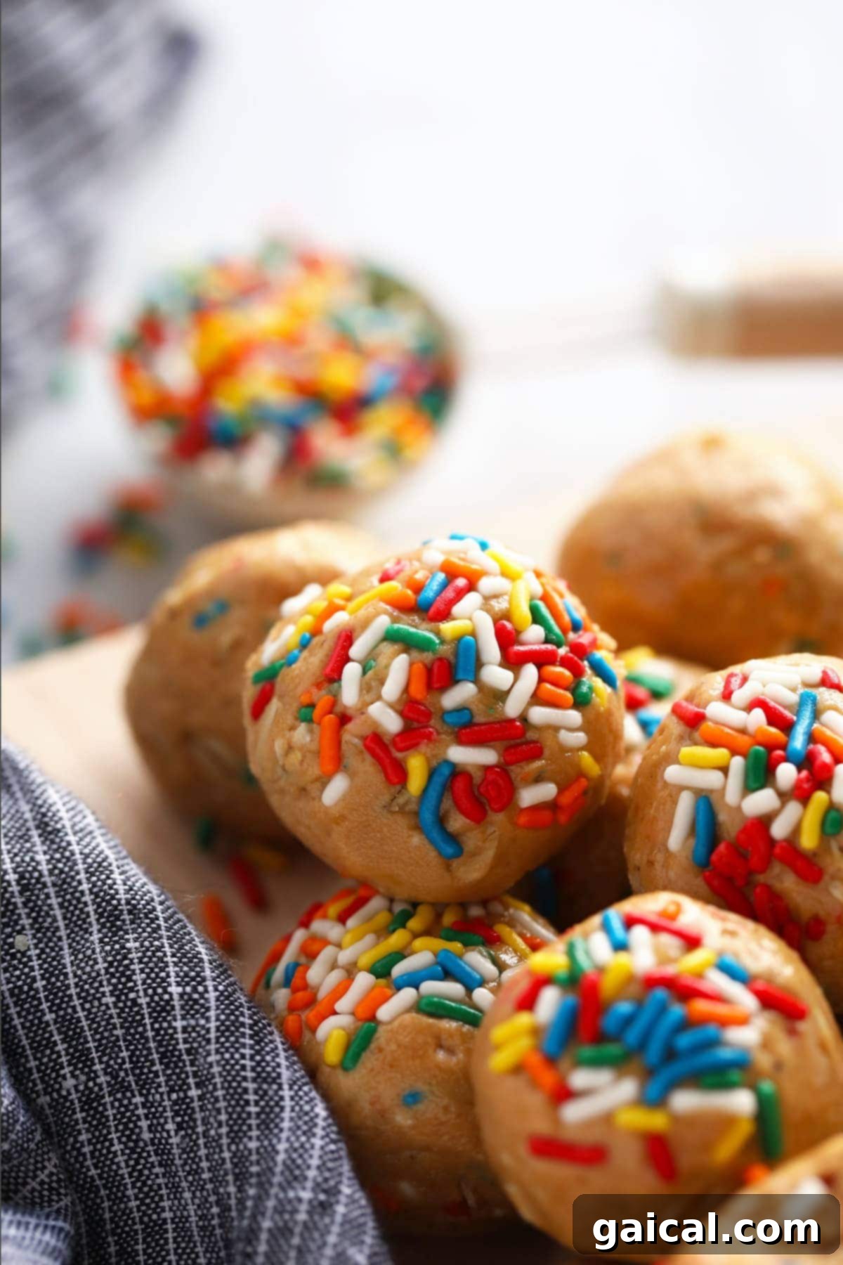 Colorful Cake Batter Protein Balls Ready to Enjoy Beautifully arranged cake batter protein balls, generously coated in rainbow sprinkles, presented on a pristine white plate.