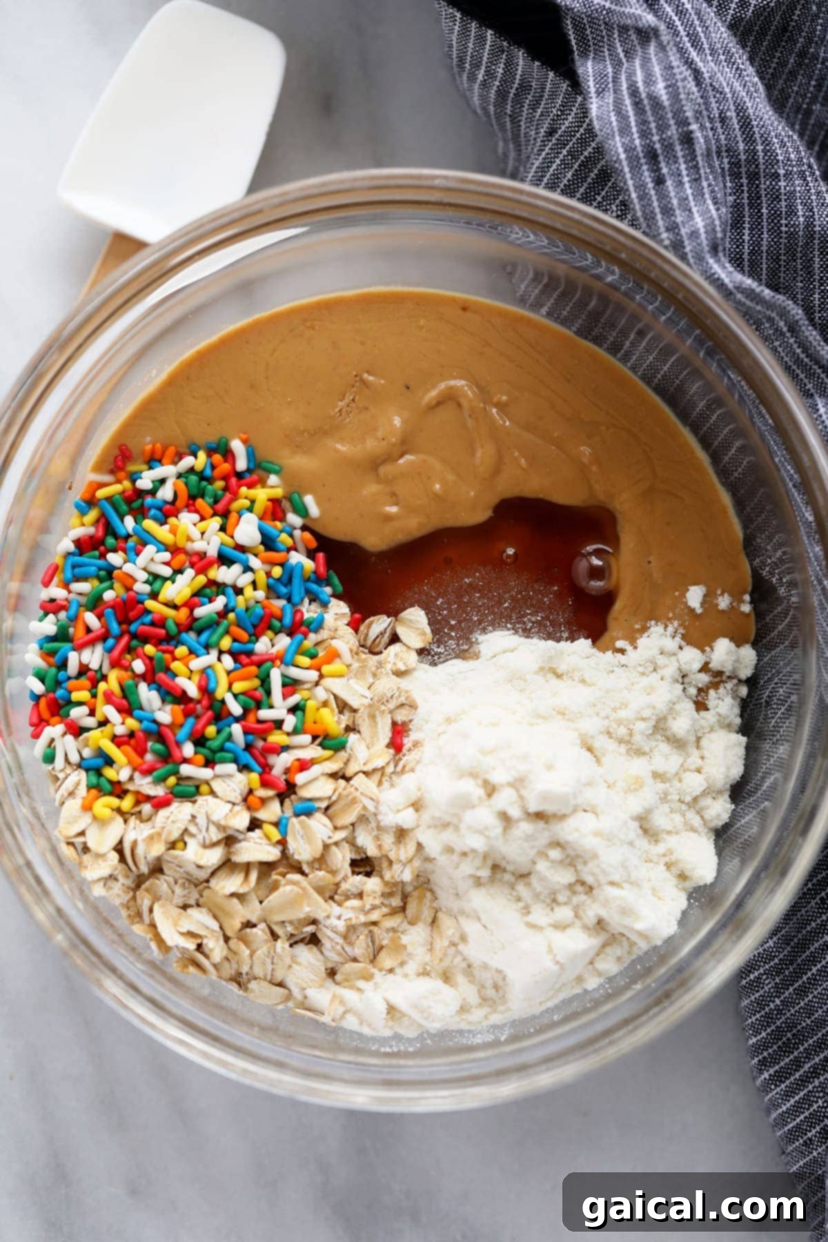 Gathered Ingredients for Cake Batter Protein Balls: Simplicity in a Bowl! A bowl filled with all the key ingredients for cake batter protein balls, ready to be mixed into a delicious dough.