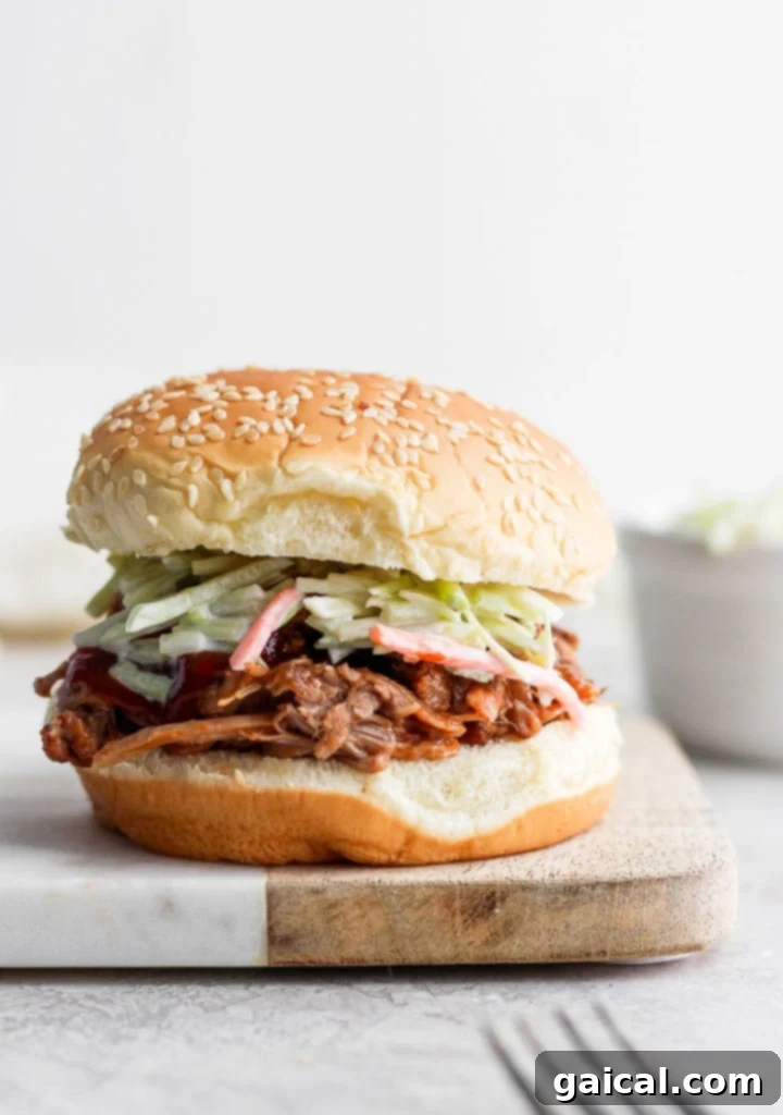 Classic Pulled Pork Sandwich A hearty pulled pork sandwich served on a bun on a wooden cutting board.