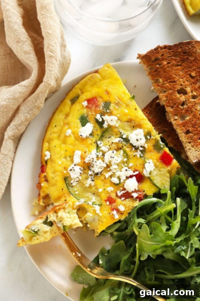 Turn your fridge full of fresh vegetables and farm-fresh eggs into a delicious, low-carb frittata, sprinkled with parmesan cheese for an extra touch of flavor! A delicious, perfectly baked vegetable frittata on a plate, garnished and ready to eat for breakfast or brunch.
