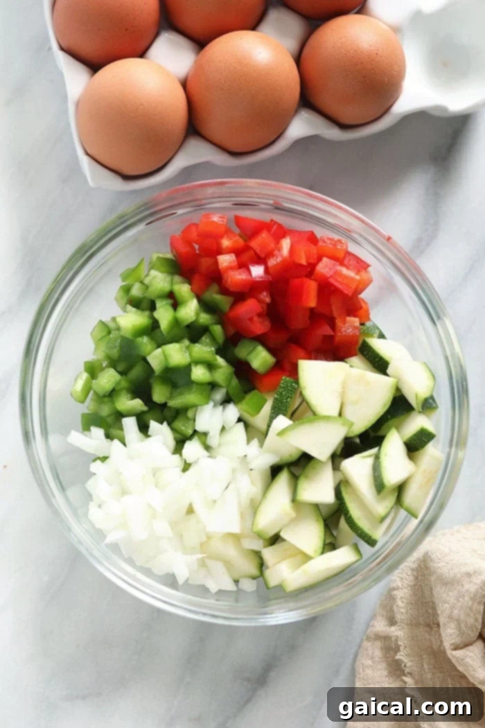 Got a bounty of fresh vegetables in your fridge? Transform them into a vibrant and delicious vegetable frittata with farm fresh eggs and a hint of parmesan for a perfect low-carb meal! Freshly diced, colorful vegetables for a frittata recipe, neatly arranged in a bowl, ready for cooking.