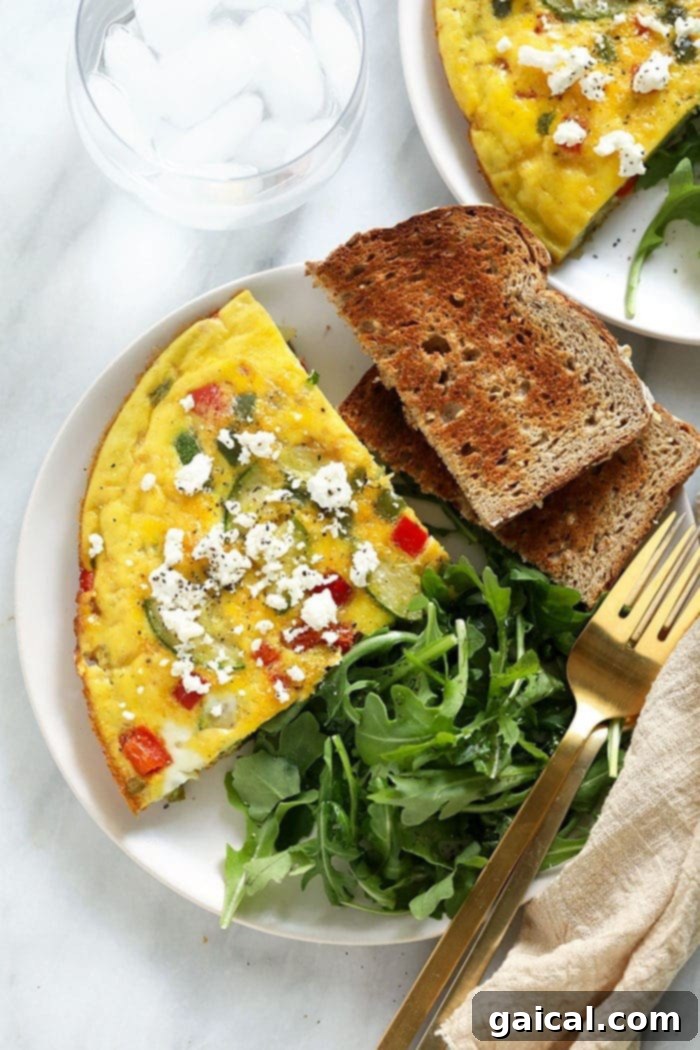 Enjoy your vegetable frittata with farm fresh eggs and a sprinkle of parmesan cheese for a low-carb breakfast option! A perfectly plated frittata, served with a side of crunchy toast and fresh arugula, creating a balanced and inviting breakfast or brunch.