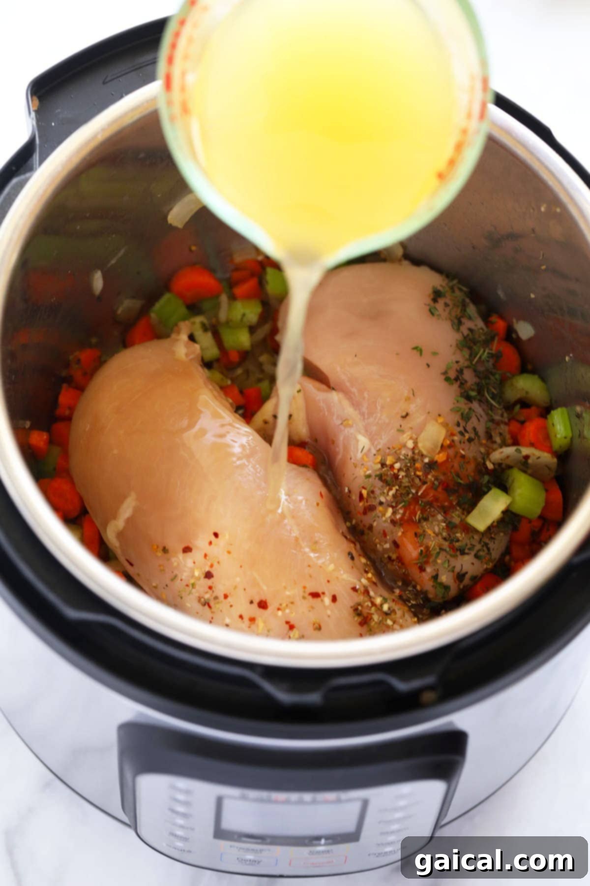 Effortless Instant Pot Chicken Noodle Soup 3 Various fresh ingredients for Instant Pot Chicken Noodle Soup laid out on a wooden board: chicken breast, carrots, celery, onion, herbs, and spices.