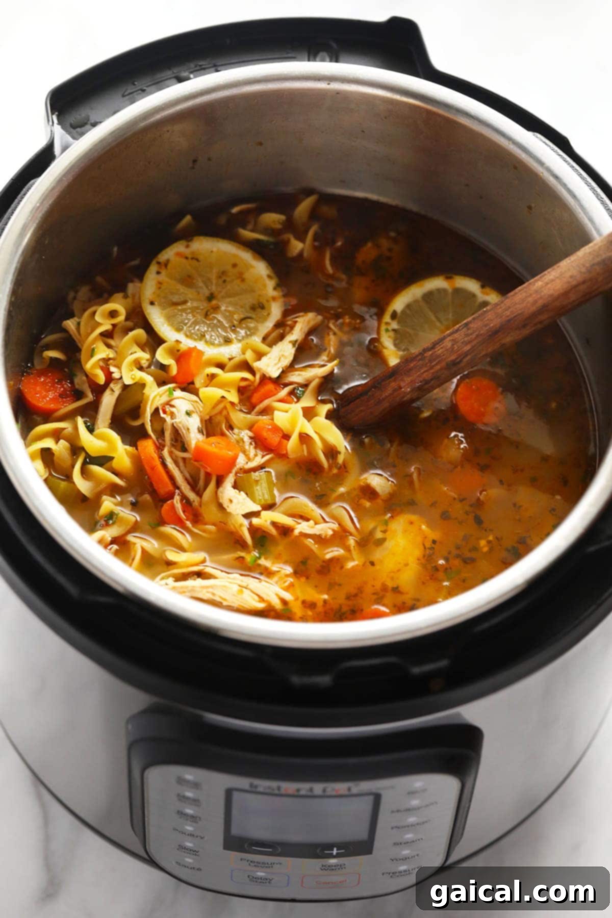 The most flavorful Instant Pot Chicken Noodle Soup made with tons of veggies, tender chicken, egg noodles, and an incredibly tasty broth! Instant Pot chicken Noodle Soup in Instant Pot with wooden spoon, showcasing the hearty texture and comforting appeal.