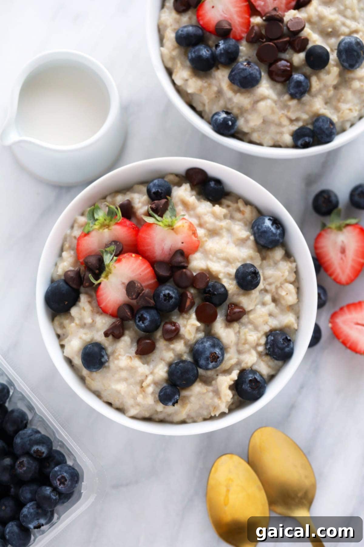Easy Instant Pot Oatmeal made with old fashioned oats instead of steel cut made in less than half the time! Two steaming bowls of creamy Instant Pot Oatmeal, garnished with fresh berries and nuts, ready to be enjoyed as a healthy breakfast.