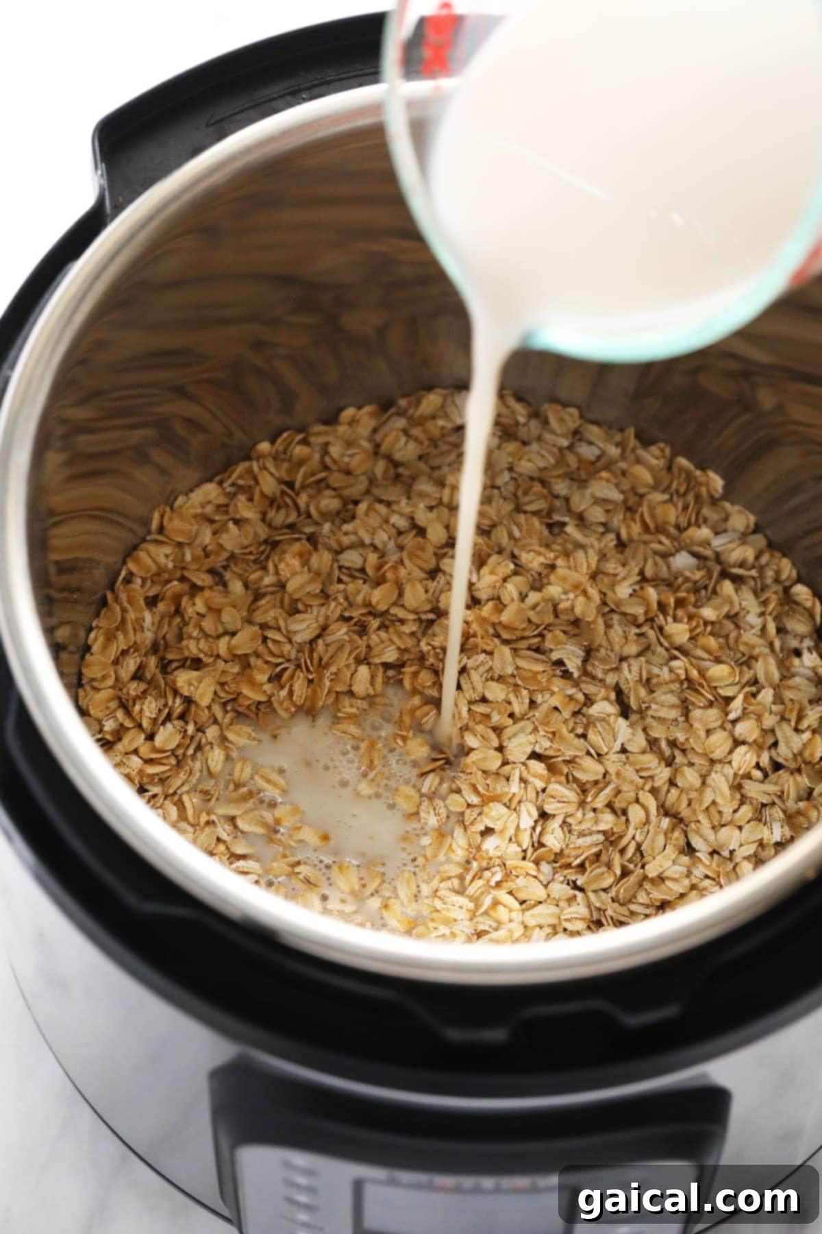 Instant Pot Oatmeal is a healthy breakfast packed with fiber and protein. This Instant Pot Oatmeal recipe is naturally vegan and gluten-free! Pouring almond milk into the Instant Pot inner pot, where rolled oats and other ingredients are already waiting.