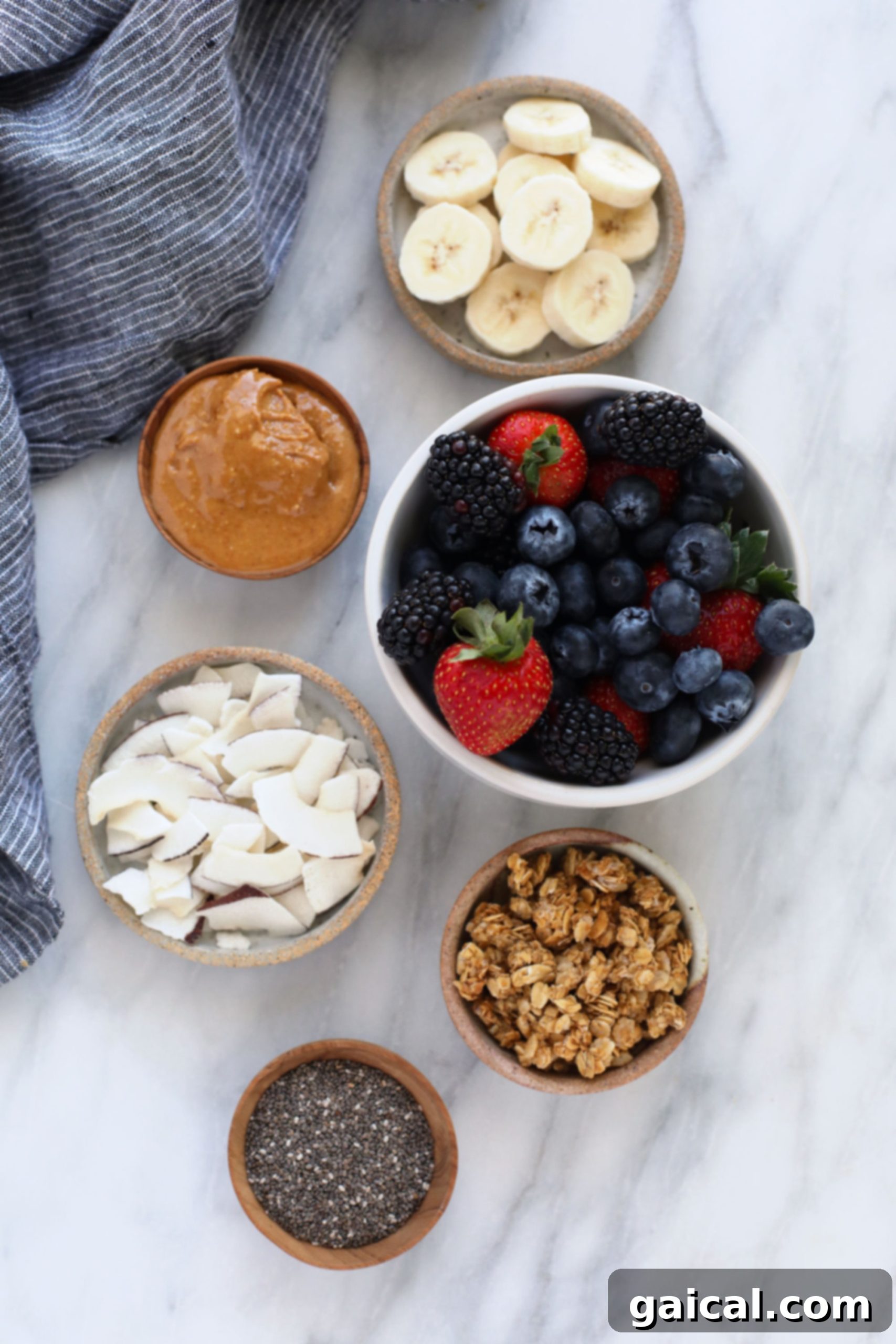 Smoothie Bowl Variations 5 Close-up of a smoothie bowl with an assortment of toppings including fresh berries, crunchy granola, creamy peanut butter drizzle, coconut flakes, chia seeds, and banana slices.