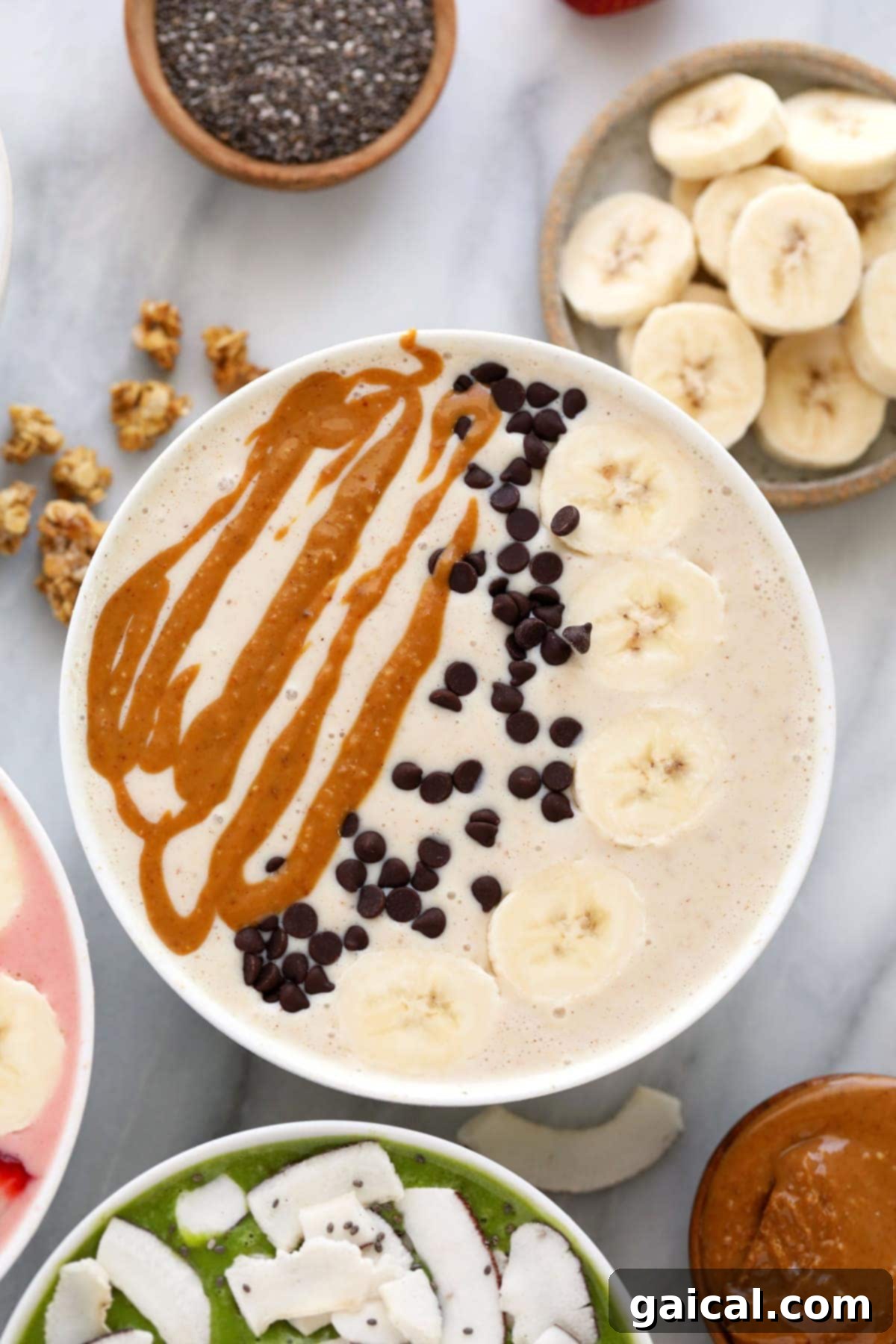 Smoothie Bowl Variations 7 A creamy peanut butter banana smoothie bowl generously topped with fresh banana slices, mini chocolate chips, and a rich swirl of peanut butter.