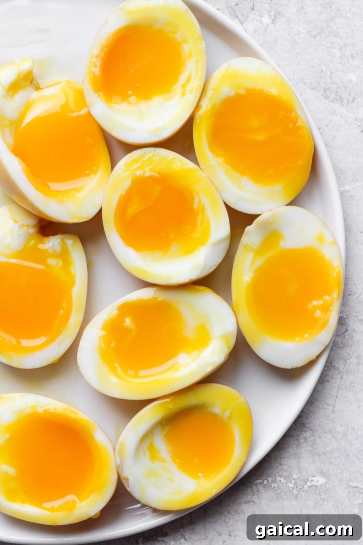 Speedy Jammy Ramen Eggs 2 Soft-boiled black tea and ginger ramen eggs perfectly sliced on a small plate, ready to be served or added to ramen, showcasing their tender whites and jammy yolks.