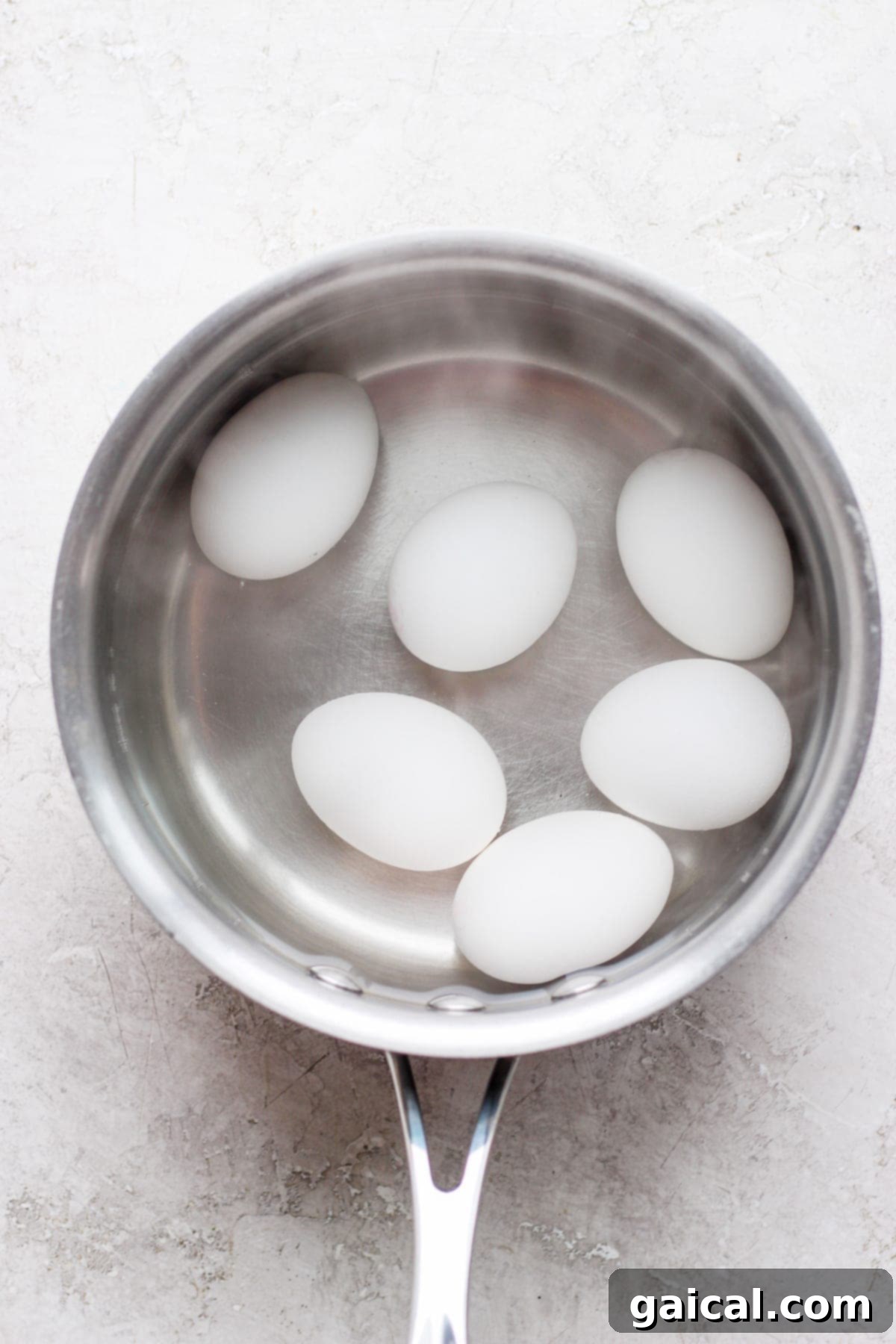Speedy Jammy Ramen Eggs 4 Fresh eggs carefully placed into a saucepan of boiling water, beginning the precise cooking process for perfect soft-boiled ramen eggs.
