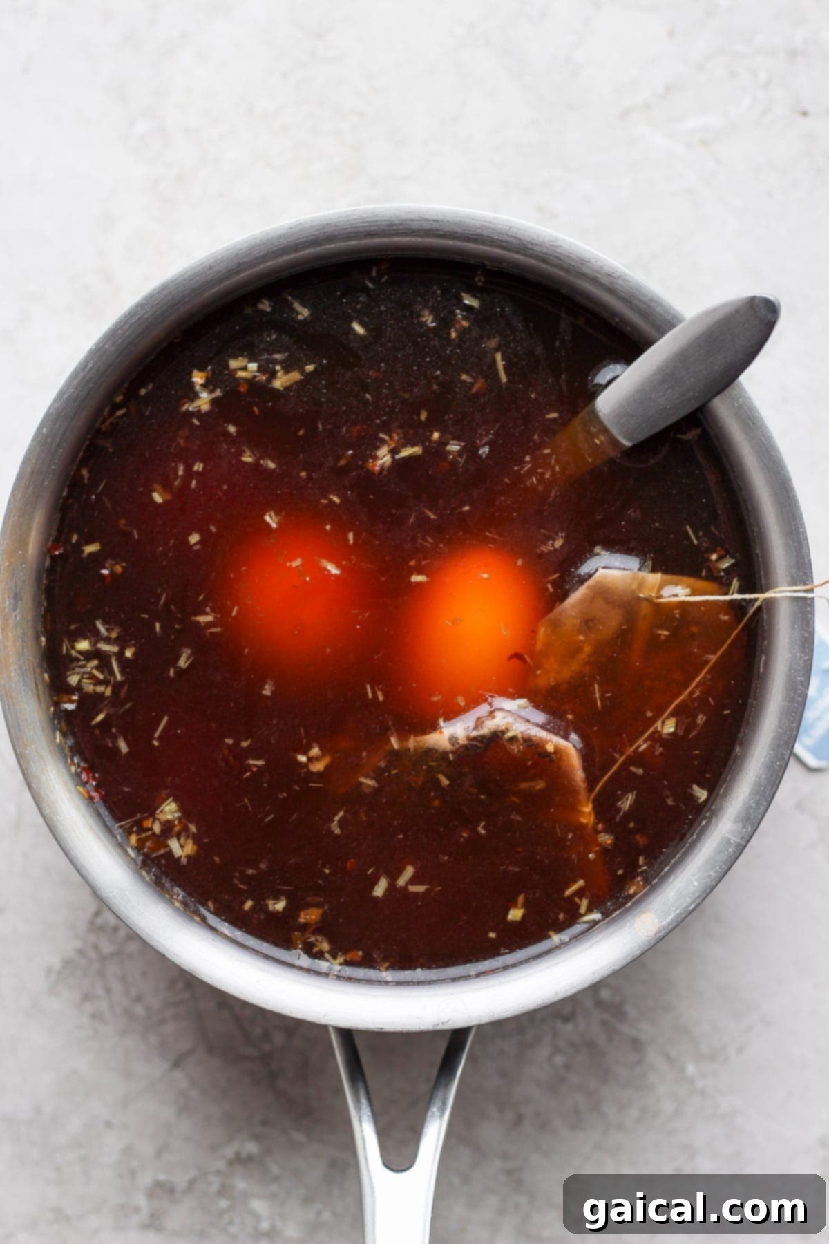 Speedy Jammy Ramen Eggs 5 Peeled soft-boiled eggs gently marinating in a rich black tea and ginger mixture in a bowl, absorbing incredible flavors and color.