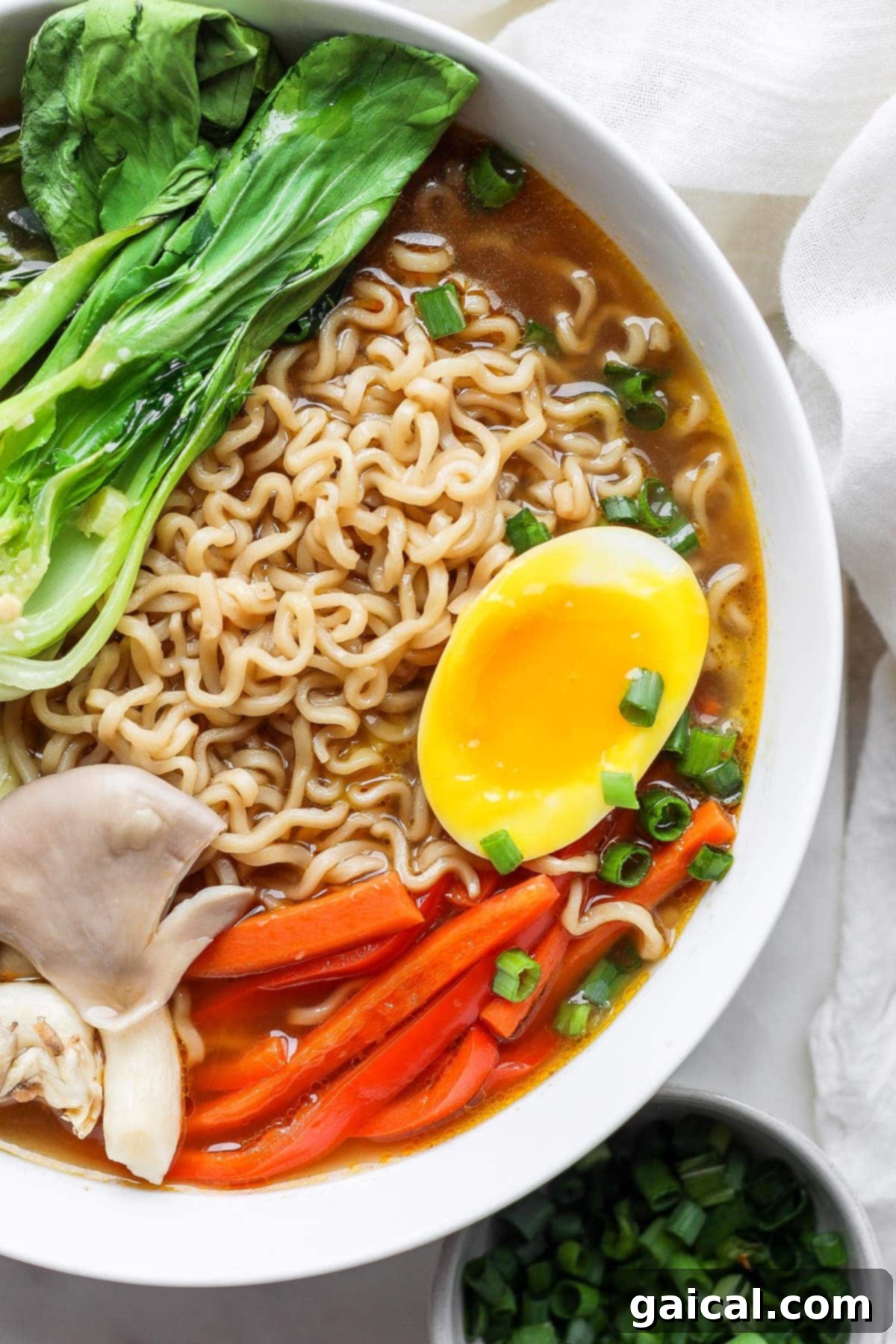 Speedy Jammy Ramen Eggs 7 A steaming bowl of flavorful ramen noodle soup, expertly garnished with a perfectly sliced black tea ramen egg, vibrant green onions, and other delicious toppings.