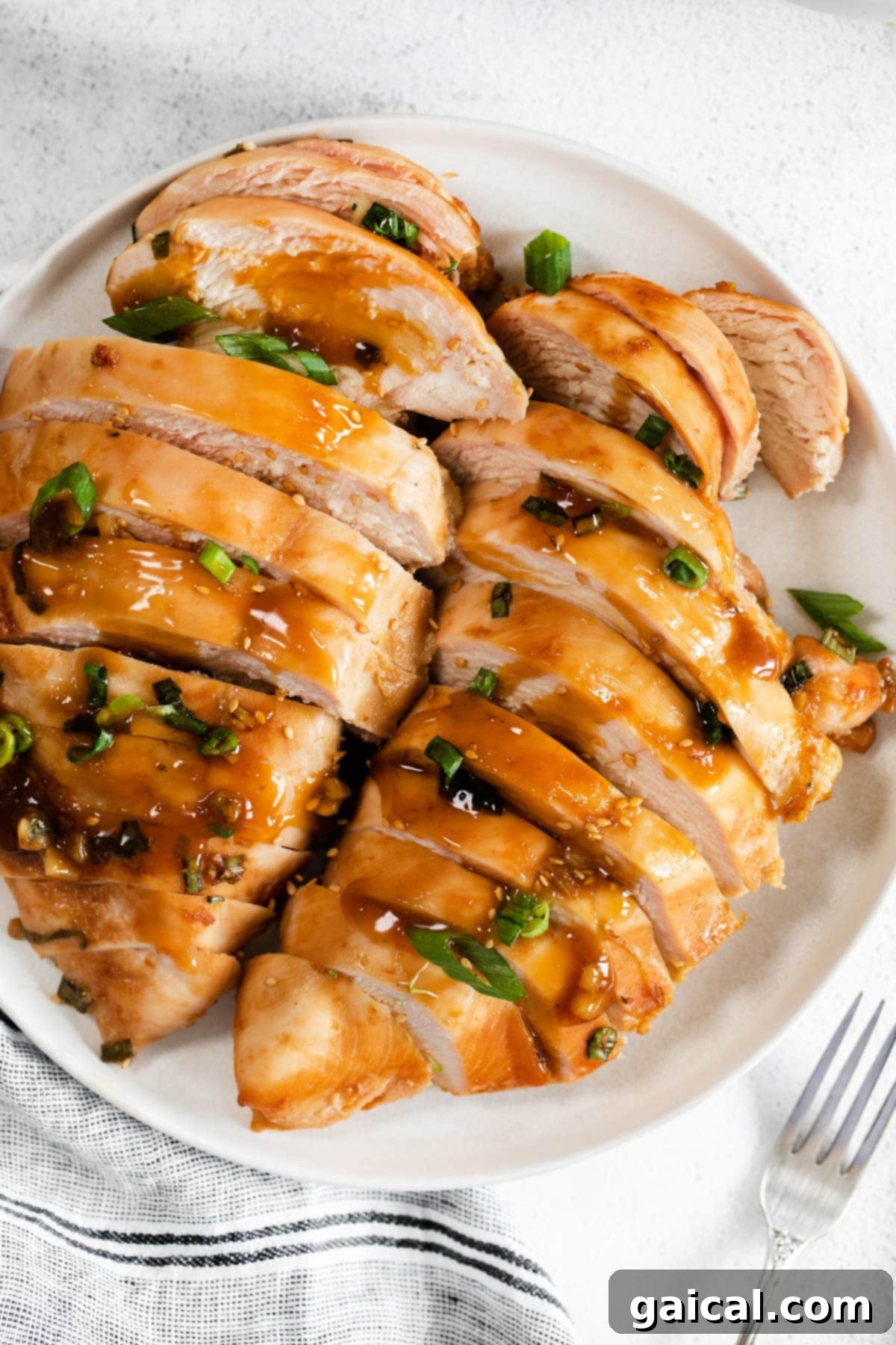 When in doubt, make this easy Baked Teriyaki Chicken Breast. The chicken is marinated in an easy homemade teriyaki chicken marinade and then baked in a casserole dish until tender. Beautifully sliced teriyaki chicken breast arranged on a plate, garnished with green onions.