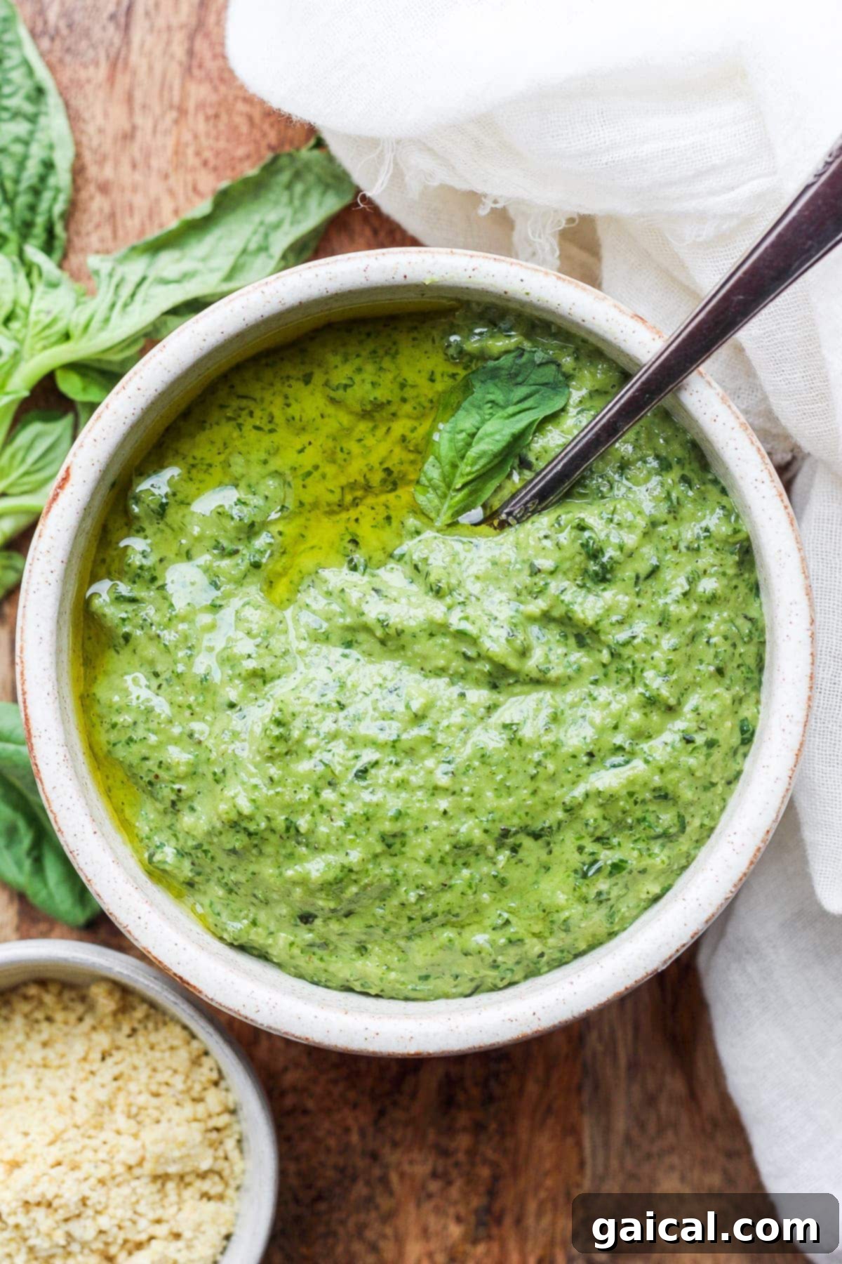 A rustic bowl filled with fresh vegan pesto, artfully garnished with a single basil leaf.