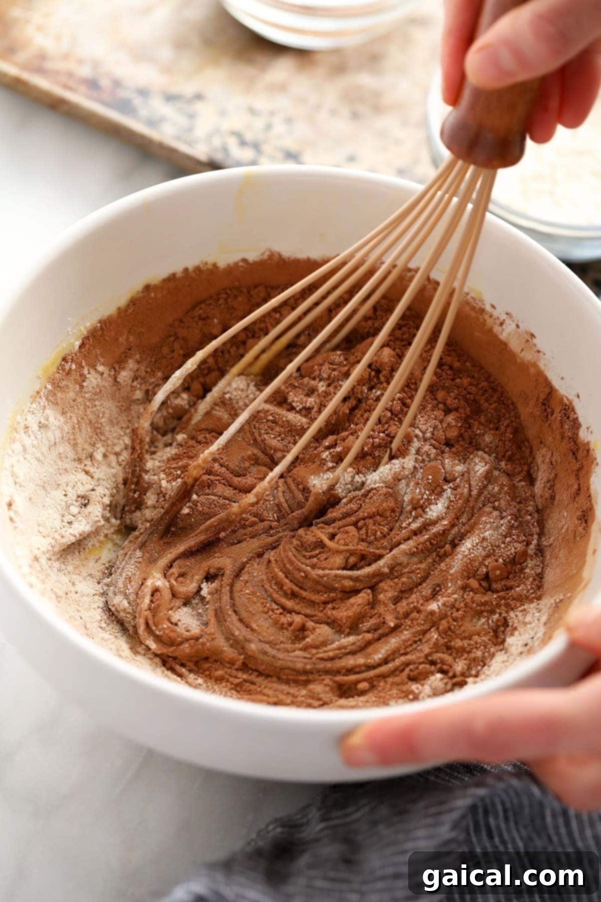 Whisking together flour and cocoa powder in a bowl for brownie batter