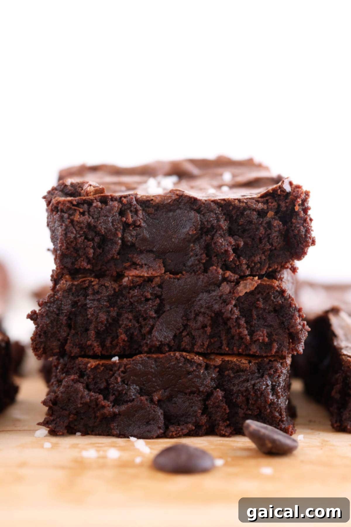 Three fudgy brownies stacked on top of each other, showing their rich texture