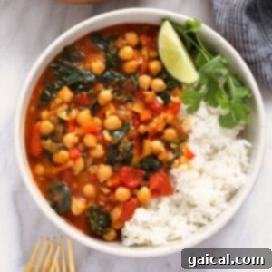 A close-up shot of a vibrant chickpea curry in a bowl, garnished with fresh herbs and served with rice.