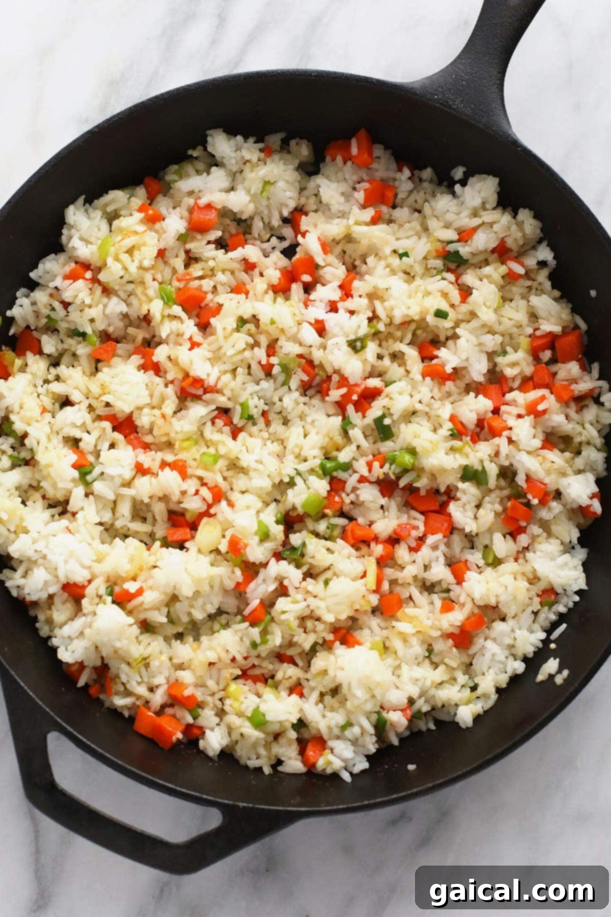 Sautéing a colorful mix of rice and various vegetables in a large cast iron pan for a wholesome meal.