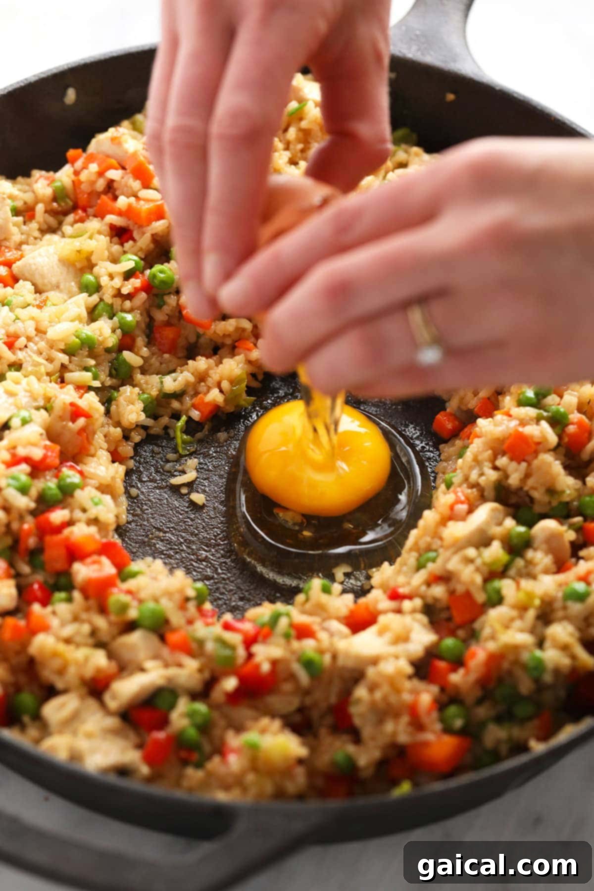 Cracking fresh eggs into the center of a hot frying pan, creating a well to scramble them for fried rice.