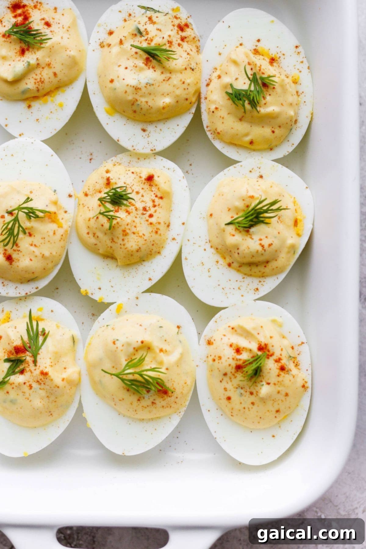 Deviled eggs elegantly presented for serving. A beautiful platter of easy deviled eggs arranged artfully in a serving dish, garnished with paprika and dill, ready to be picked up.
