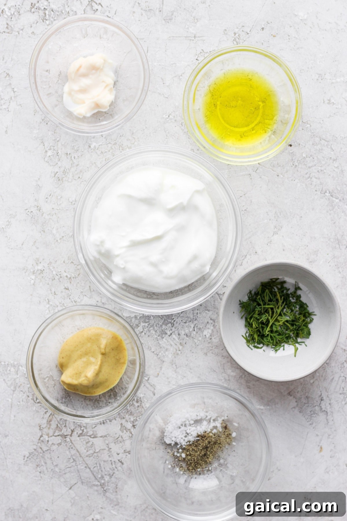 Fresh ingredients ready for the creamy deviled egg filling. Individual ingredients for deviled egg filling, including Dijon mustard, Greek yogurt, mayonnaise, pickle juice, and fresh dill, arranged beautifully before mixing.