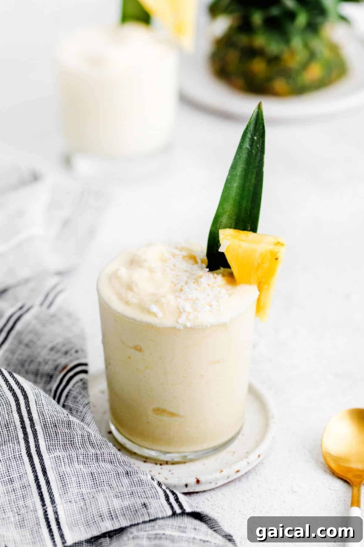 Delicious Piña Colada in a glass, garnished with a fresh pineapple chunk and a leaf, set against a bright, inviting background.