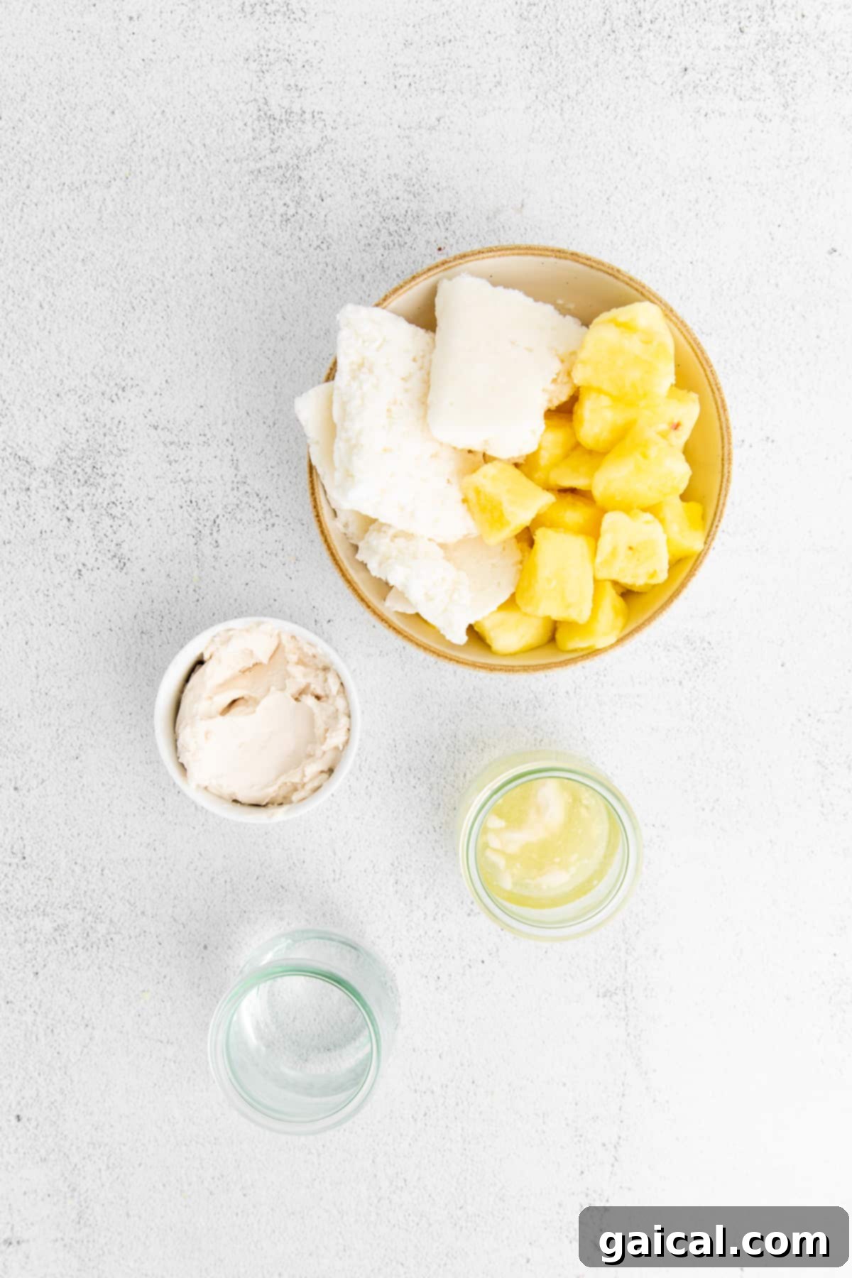 Key ingredients for a Piña Colada displayed neatly on a countertop, including frozen pineapple, coconut meat, rum, and coconut cream.