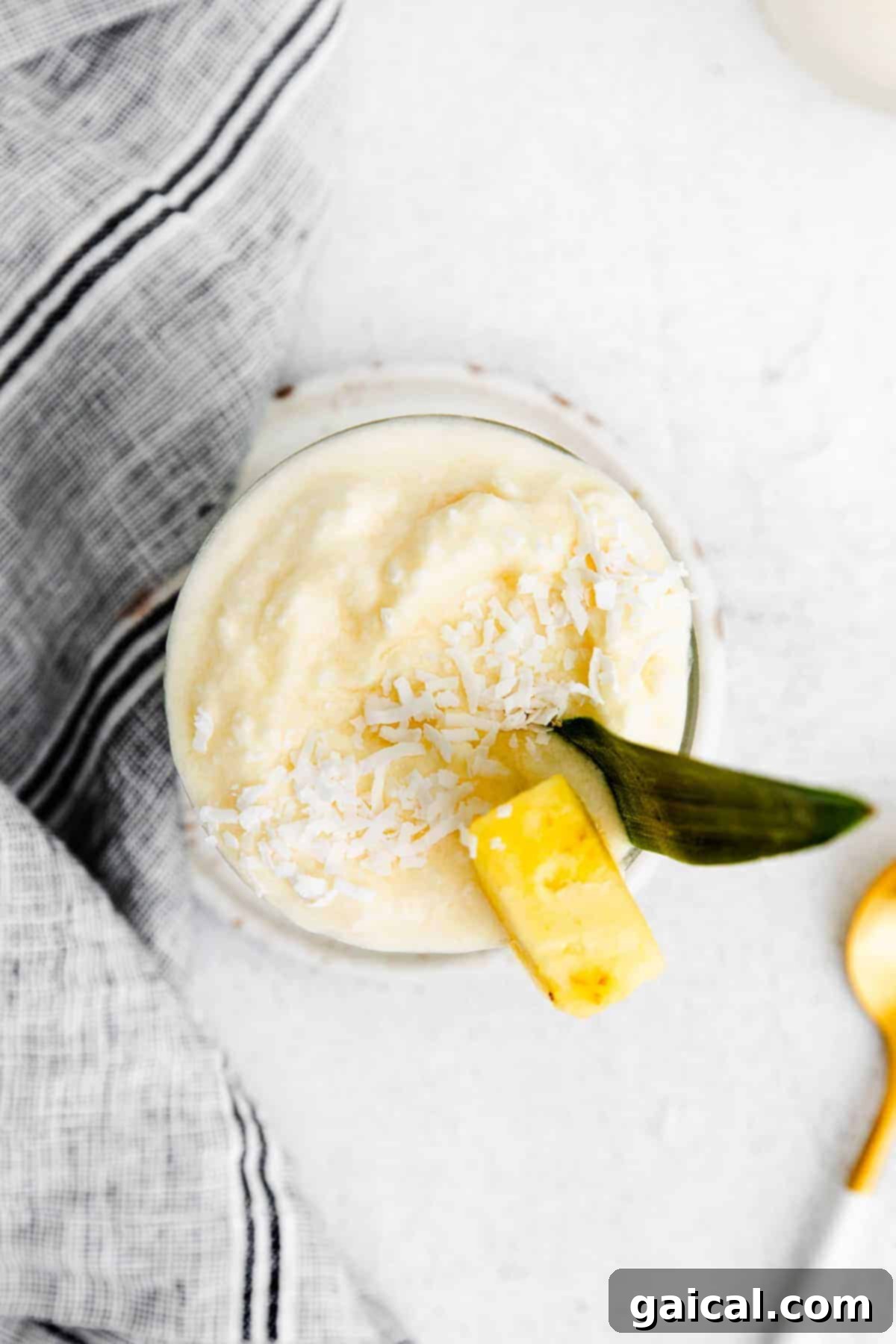 A perfectly blended Piña Colada, garnished with a fresh pineapple chunk and a vibrant straw, inviting a delightful sip.