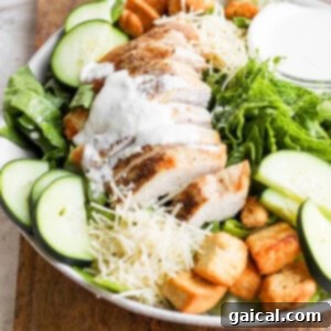Ultimate Chicken Caesar 7 A finished chicken salad with croutons and dressing, presented on a wooden cutting board, ready for serving.