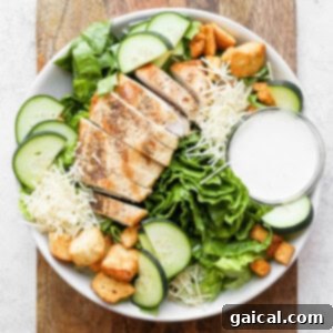Ultimate Chicken Caesar 4 A delectable chicken salad with crispy croutons and luscious dressing in a white bowl, ready to be served.
