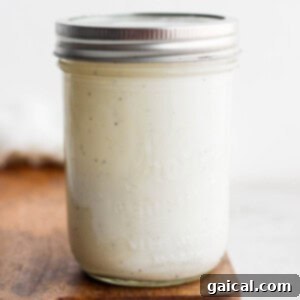 A mason jar displaying a perfectly smooth, creamy, and white Caesar dressing with a securely fastened lid.