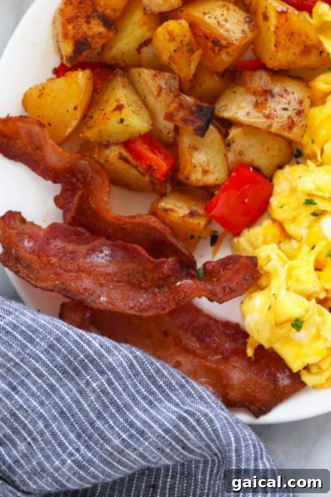 A delicious breakfast plate featuring crispy bacon, fluffy scrambled eggs, and golden breakfast potatoes.