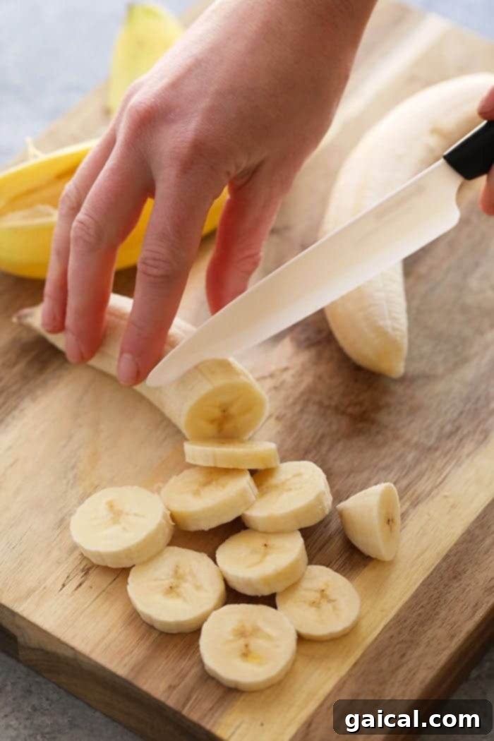 Slicing a banana for nice cream on a wooden cutting board.