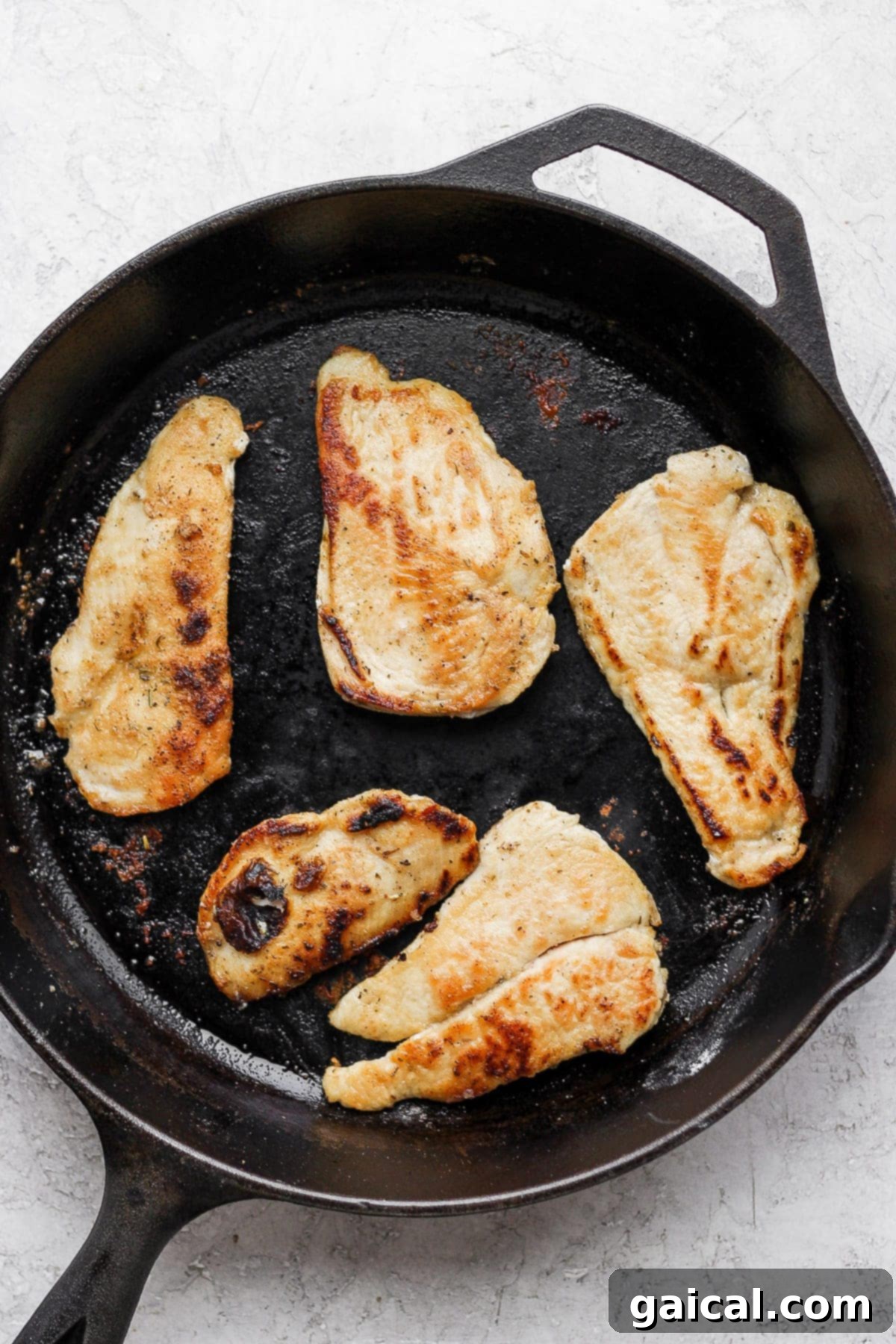 Pan-Searing Chicken for Chicken Marsala Chicken breasts being perfectly seared to a golden-brown crisp in a cast iron skillet, creating a beautiful crust before the Marsala sauce is added.
