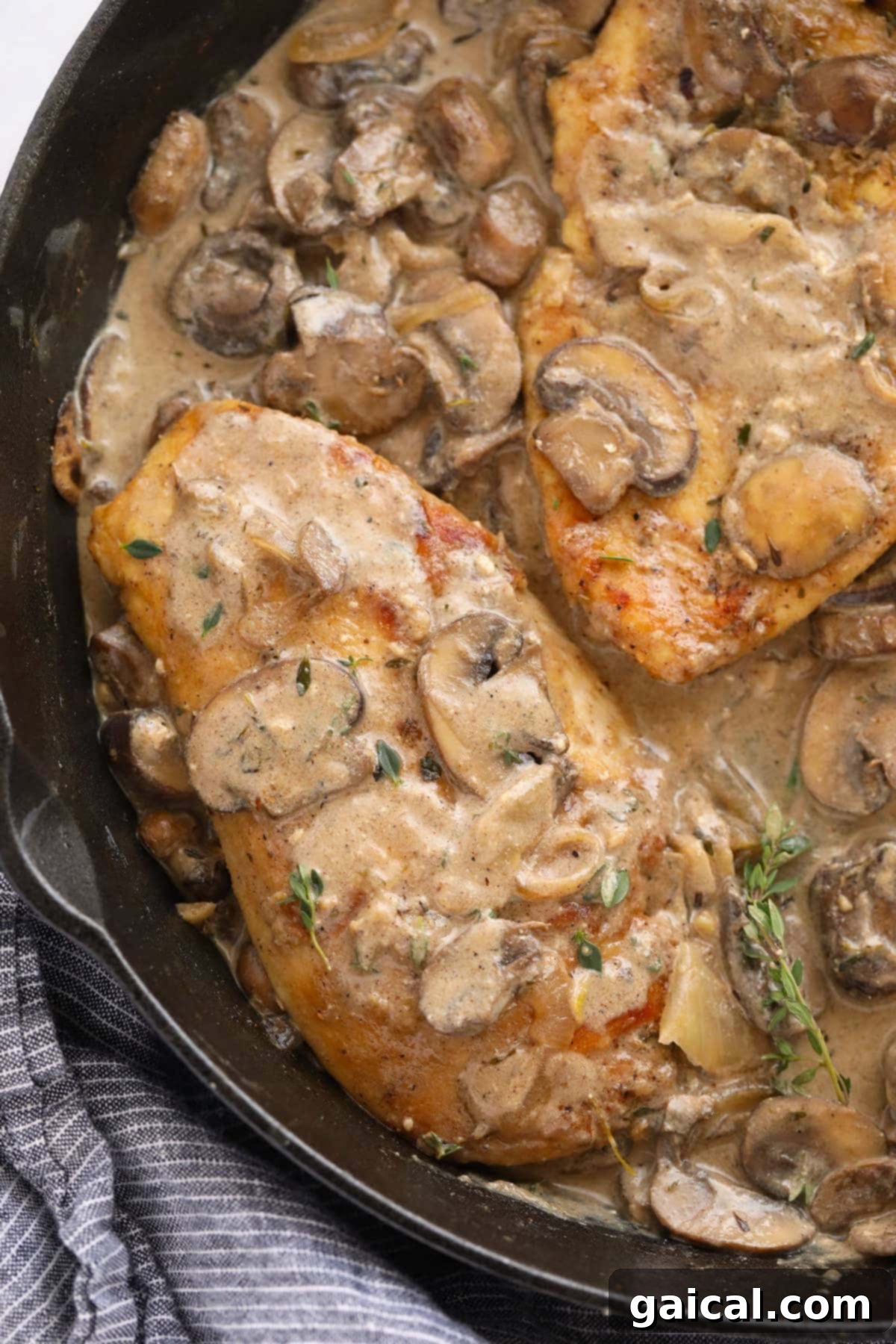Finishing Chicken Marsala with Sauce Delicious chicken Marsala sauce being generously poured over golden-brown chicken breasts in a cast iron skillet, creating a mouth-watering and rich finish.