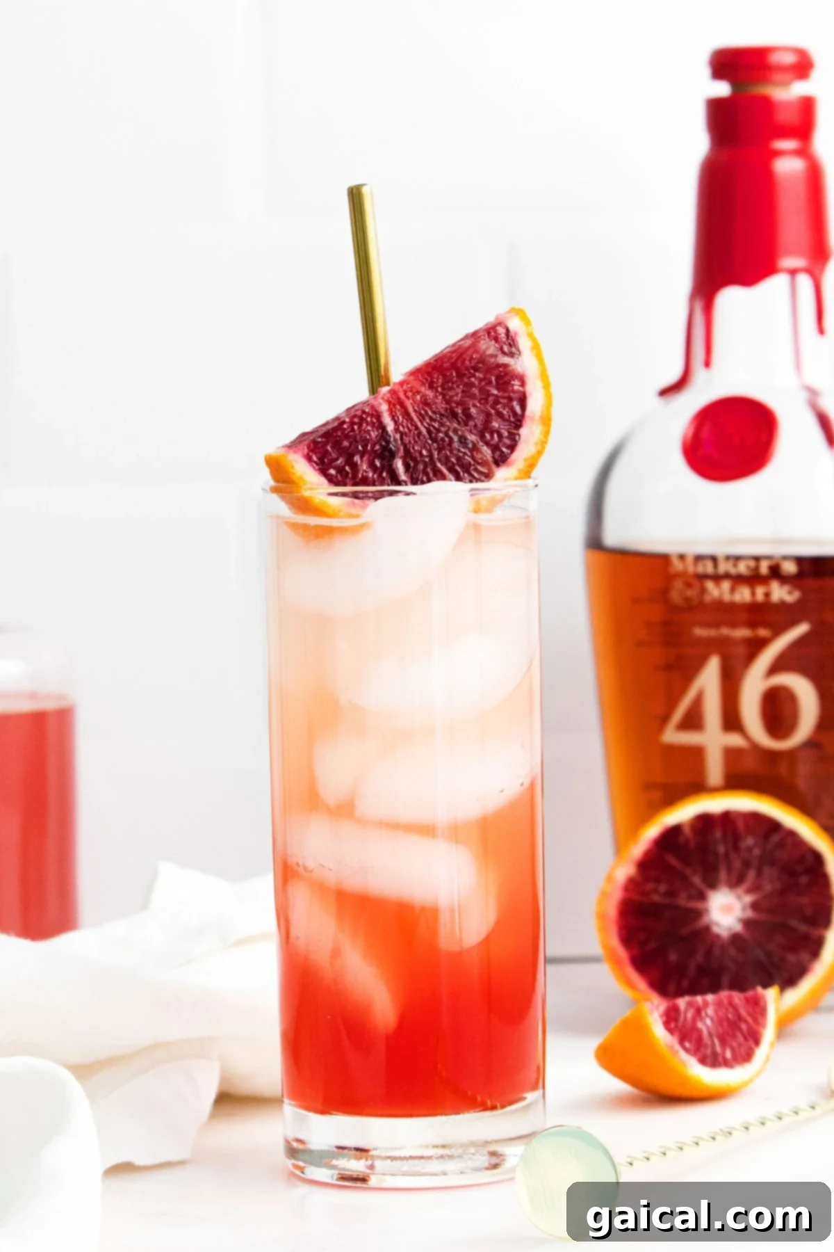 A stunning blood orange cocktail, vibrant and refreshing, served next to a bottle of bourbon, highlighting its key spirit component.