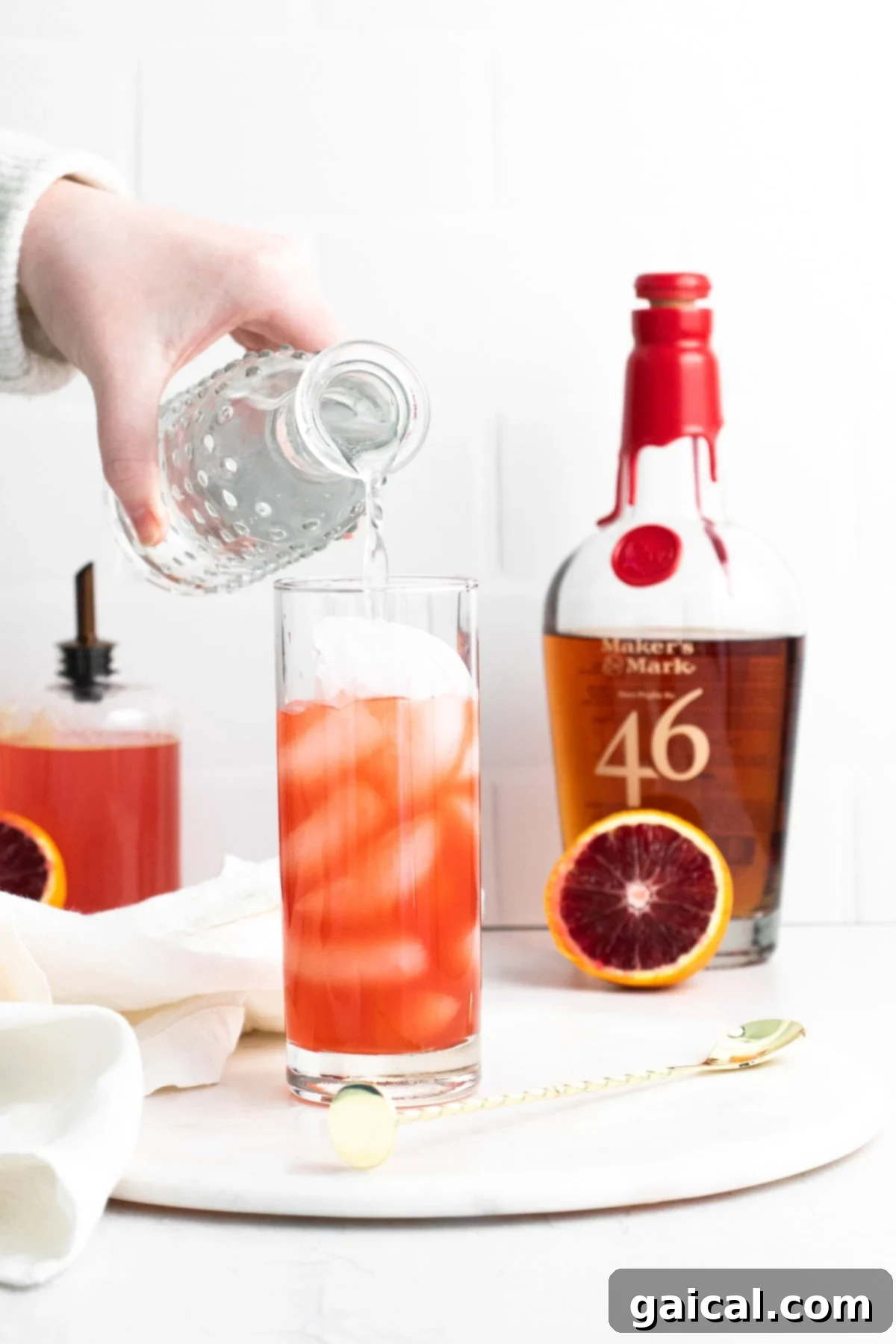 A hand reaching for a perfectly made Blood Orange Smash cocktail, inviting a refreshing sip.